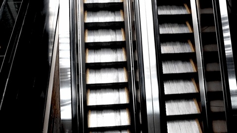Clear parallel metal escalators moving up and down gif 