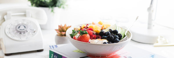 @brookelark healthy breakfast bowl of fruit, strawberries, berries on a busy desk