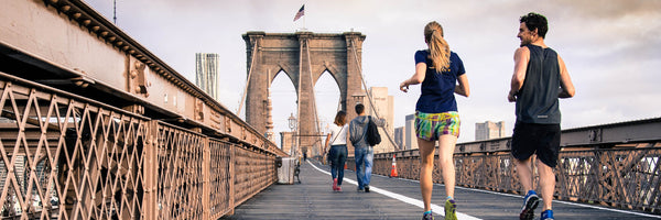 @curtismacnewton man and woman couple jogging on the brooklyn bridge in the day 