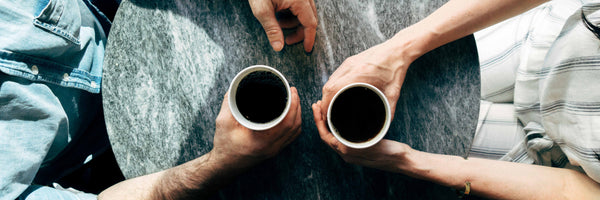 two people drinking coffee at a table
